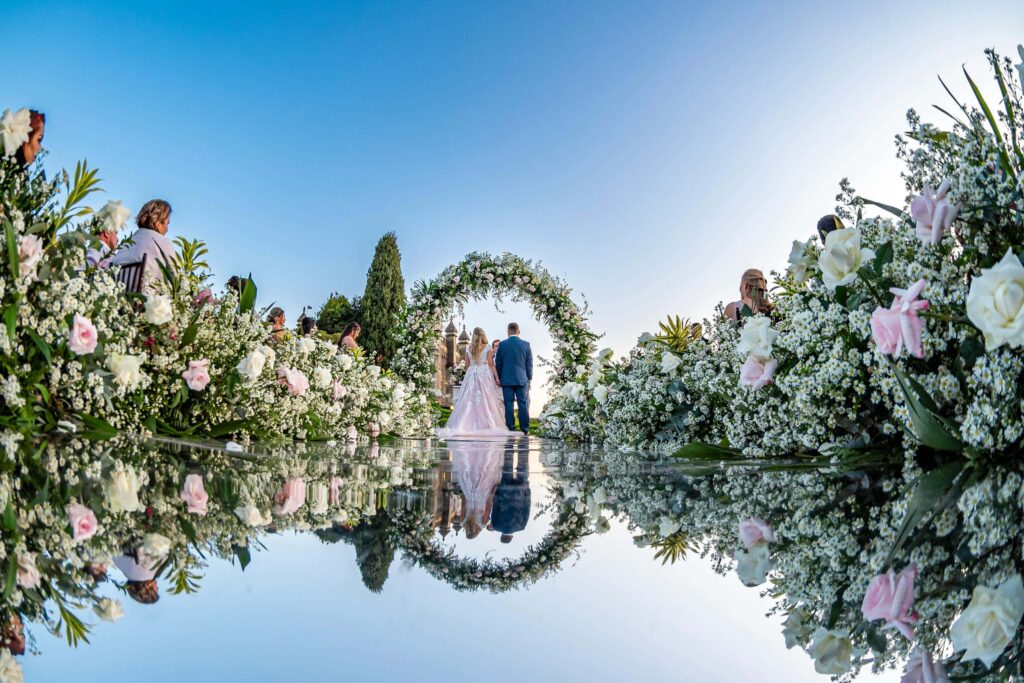 bride and groom standing at luxury wedding reception with roses in aisle